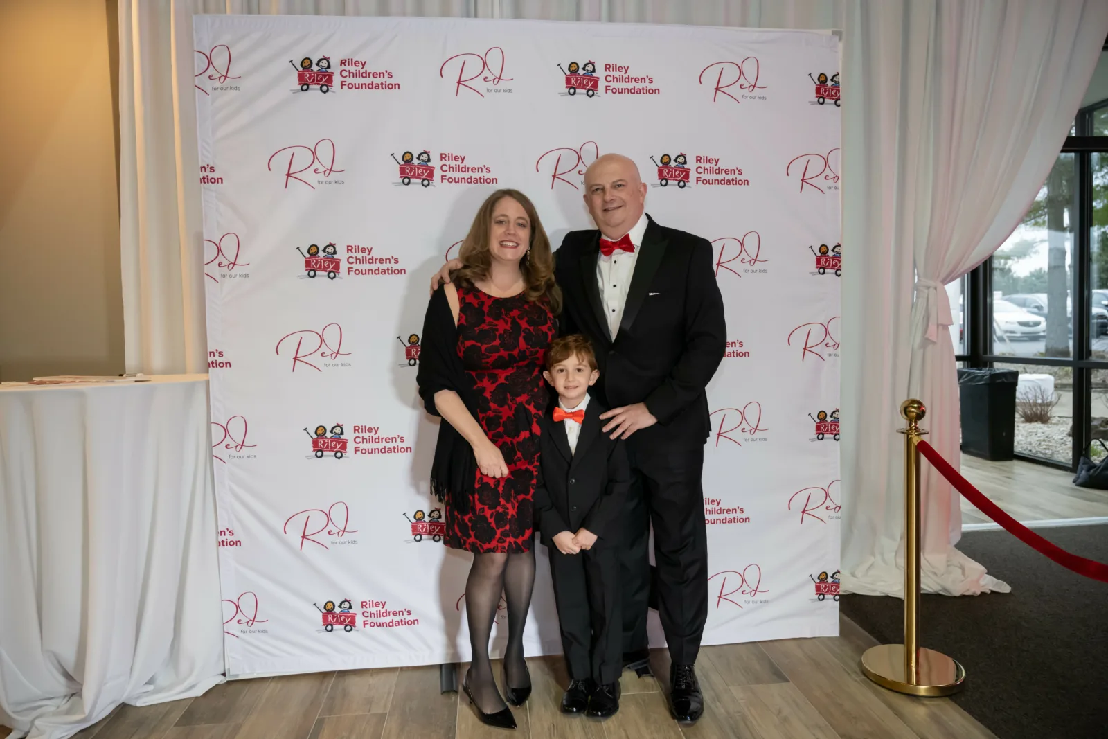 Riley family in front of Riley Red backdrop at Red event
