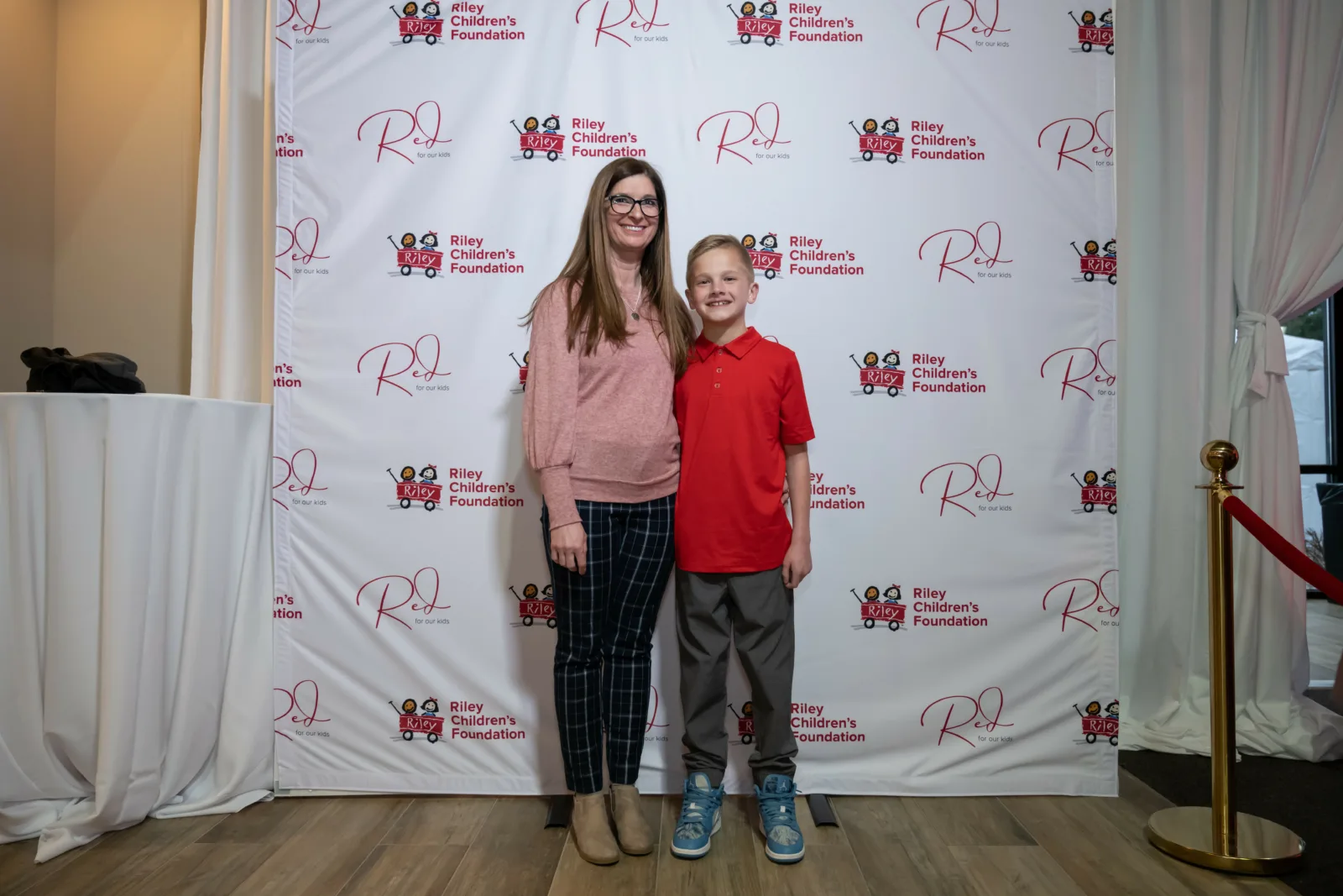 Riley family in front of backdrop with Riley wagons at Red event