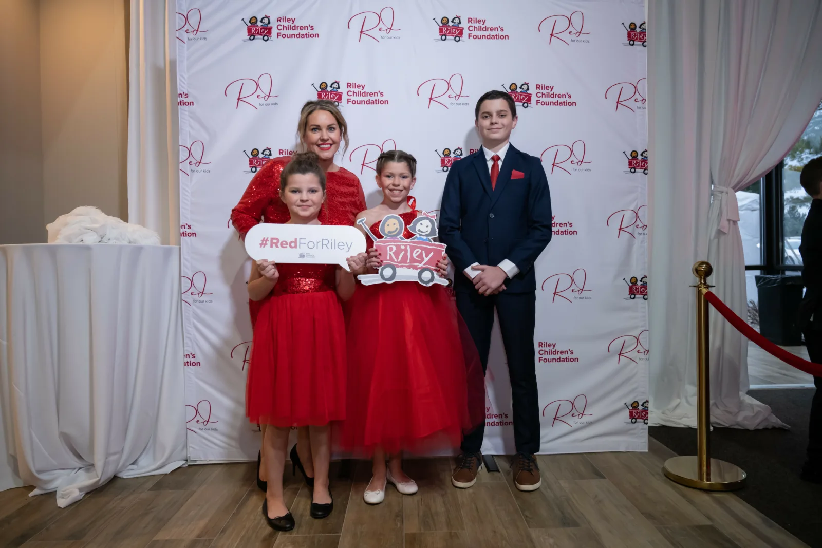 Riley kids posing in front of Riley backdrop at Riley Red event