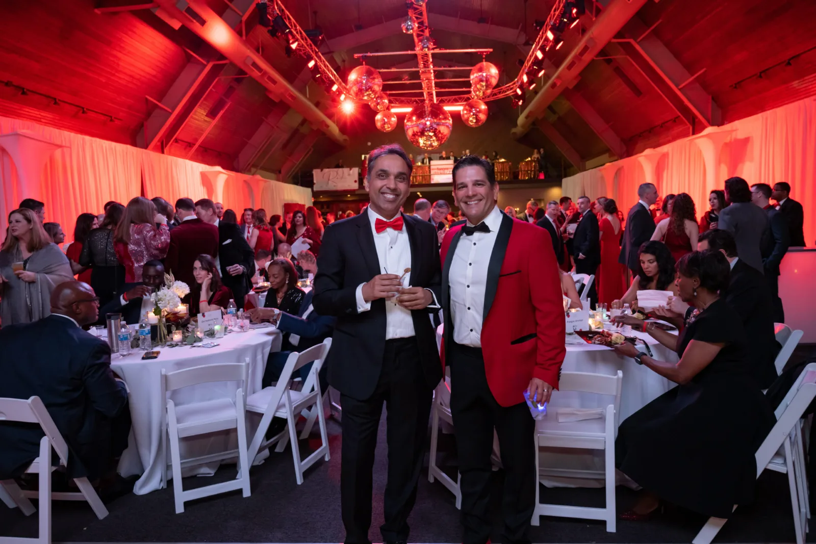 Two men posing for photo in front of dining tables.