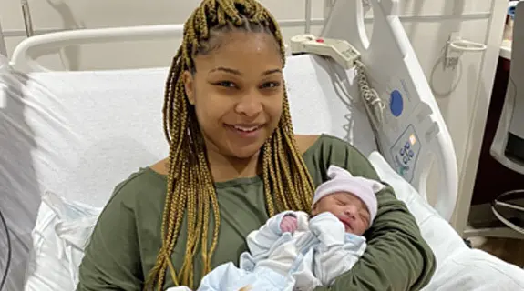 Mother holding new born baby in hospital bed.