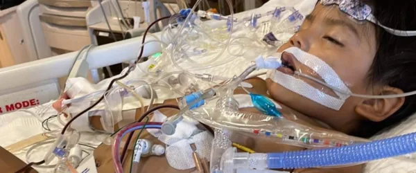 Riley kid in hospital bed with breathing tubes