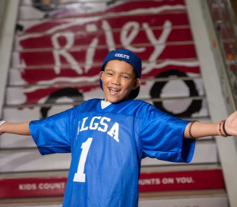 A child wearing a football jersey in front of the Riley logo